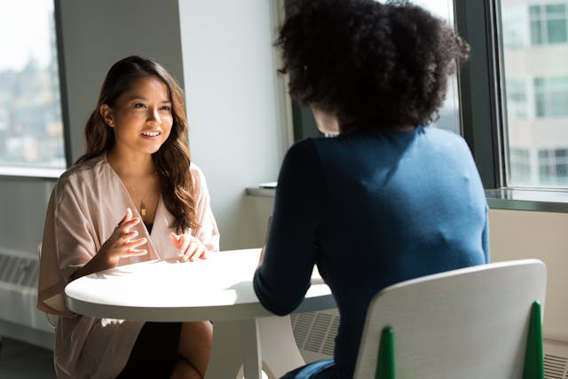 Two people sitting across from eachother at a table talking